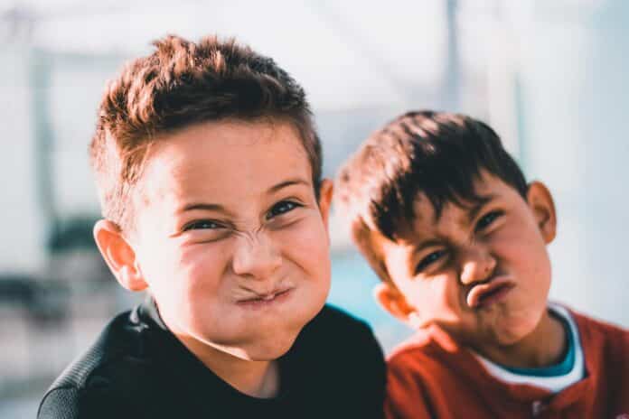 shallow focus photography of two boys doing wacky faces