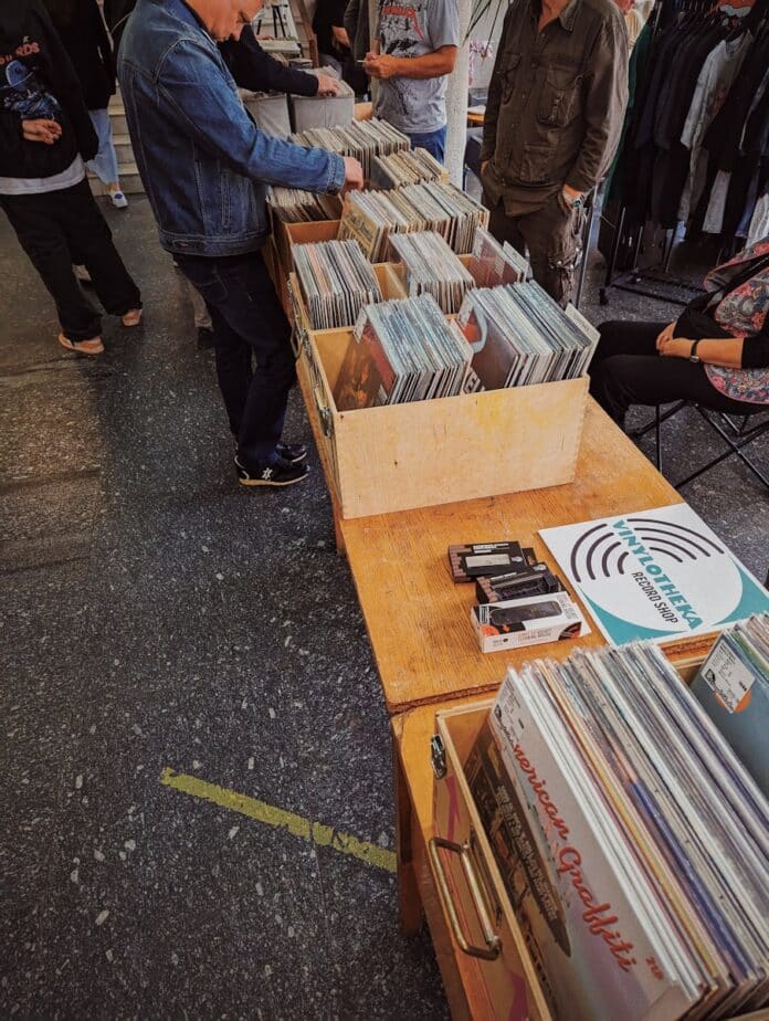 a group of people standing around a table filled with records